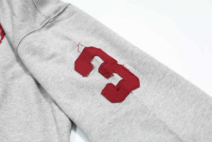 Close-up of red patch on light gray hoodie sleeve with stitched number design
