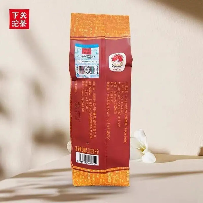 Chinese puerh tea bag with orange and red packaging, barcode, and Chinese text, upright on table