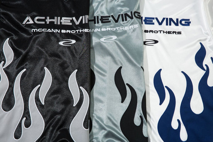 Close-up of black, silver, and white jerseys showing front logo and flame graphics