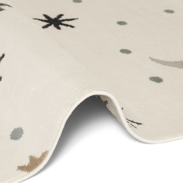 Close-up of a beige rug with black, gray, and brown abstract patterns on a white background.