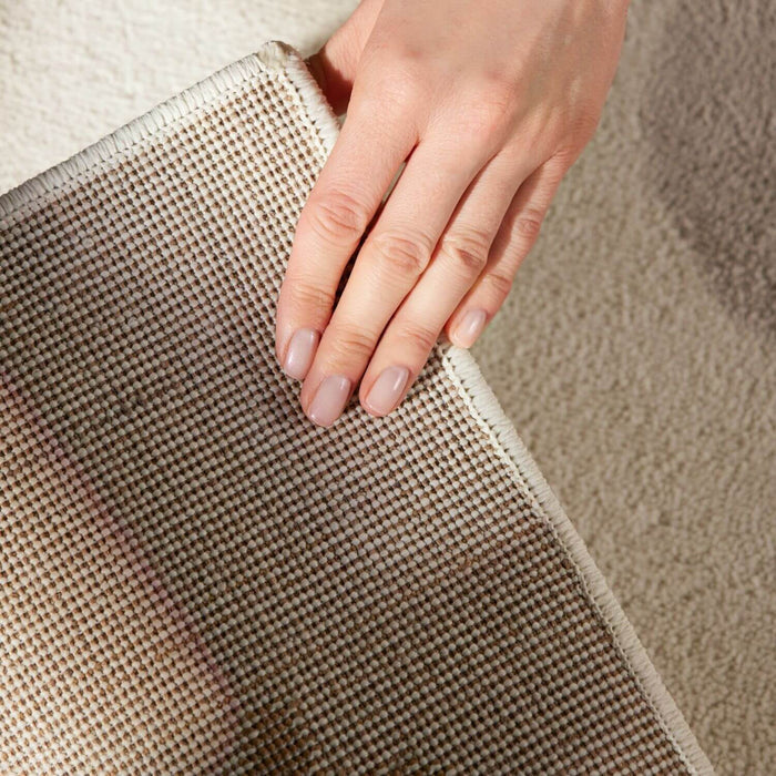 Hand touching a textured beige rug