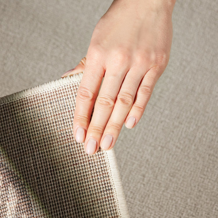 Hand holding a textured fabric against a neutral background