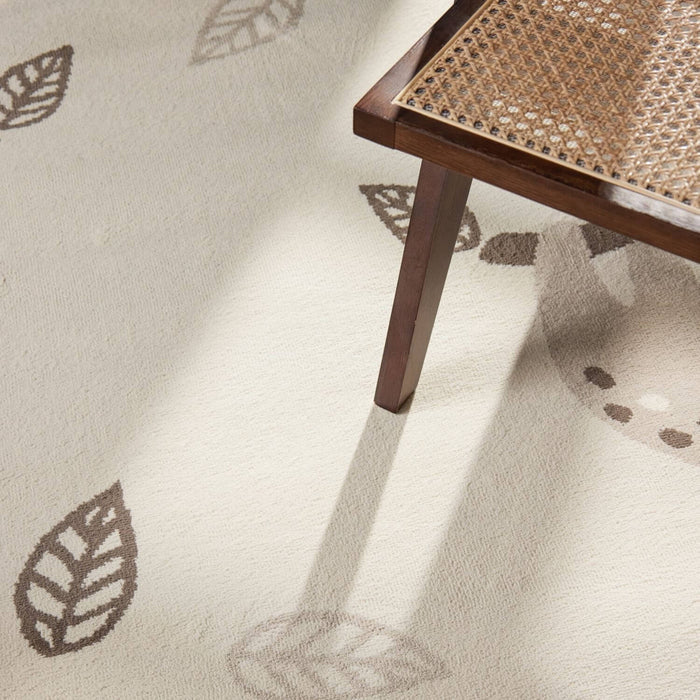 Close-up of a textured beige carpet with leaf patterns and a wooden chair leg.