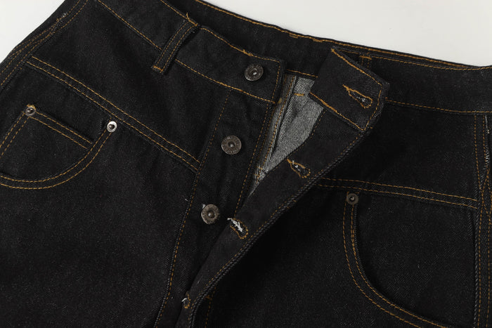 Close-up of the black denim front waist showing buttons, pocket edge, and inner lining
