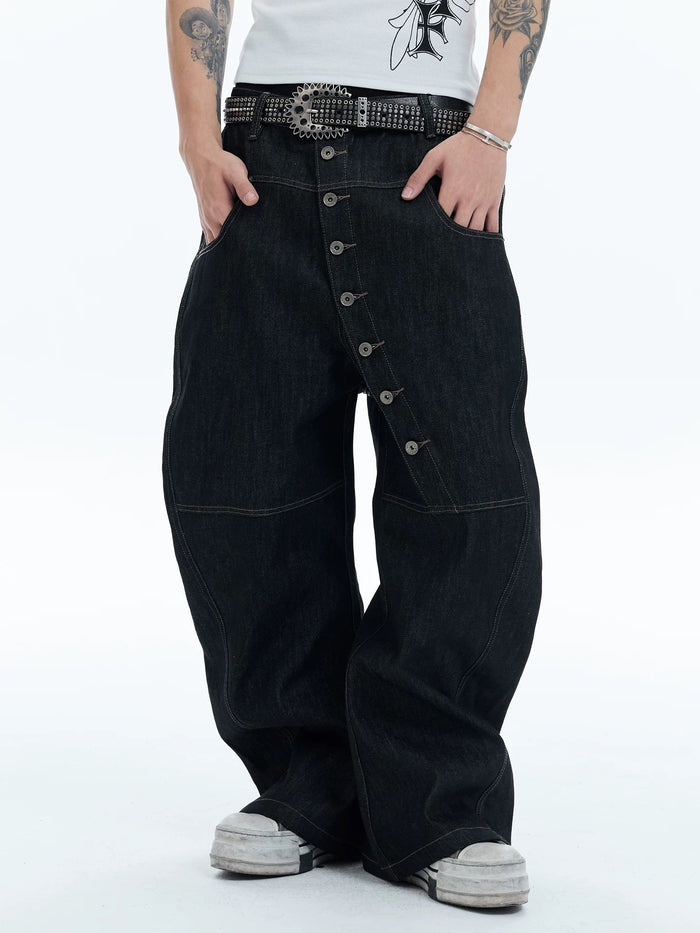 Model wearing black wide-leg balloon denim pants with asymmetric button front and studded belt