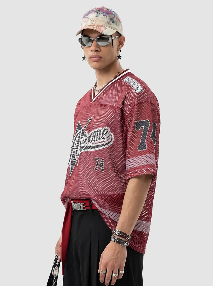 Model wearing a burgundy mesh jersey T-shirt with 74 graphic and retro varsity styling