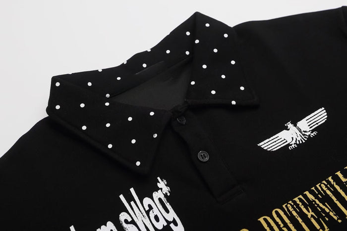 Black graphic polo shirt with white polka dot collar, eagle print, and gold streetwear lettering