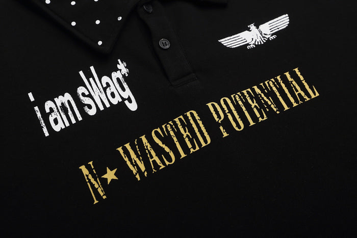 Black graphic polo shirt with studded collar, white and gold distressed text, and eagle print on chest