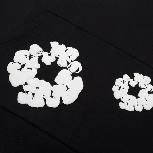 The Black "Cotton Wreath" Denim Tears Hoodie features white floral ring prints resembling popcorn-shaped clusters for a standout streetwear look.