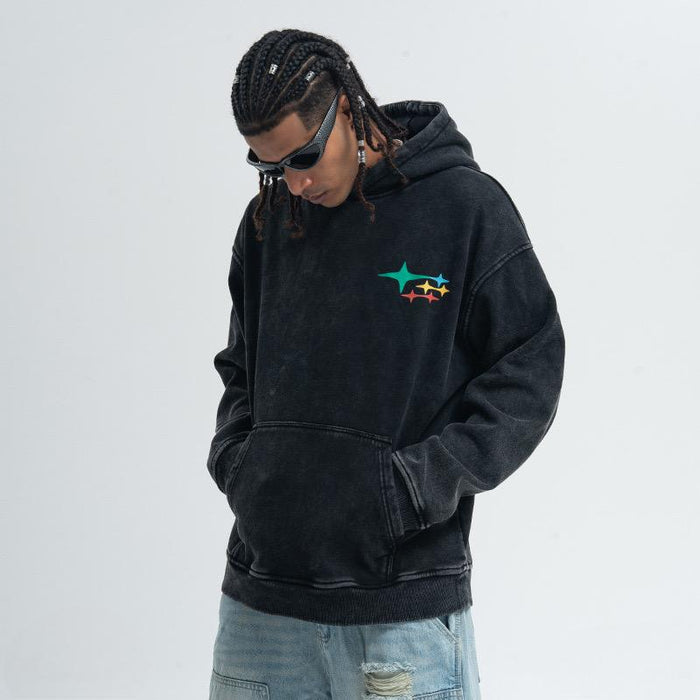 Black washed pullover hoodie with small multicolor star graphic on chest, worn with front kangaroo pocket
