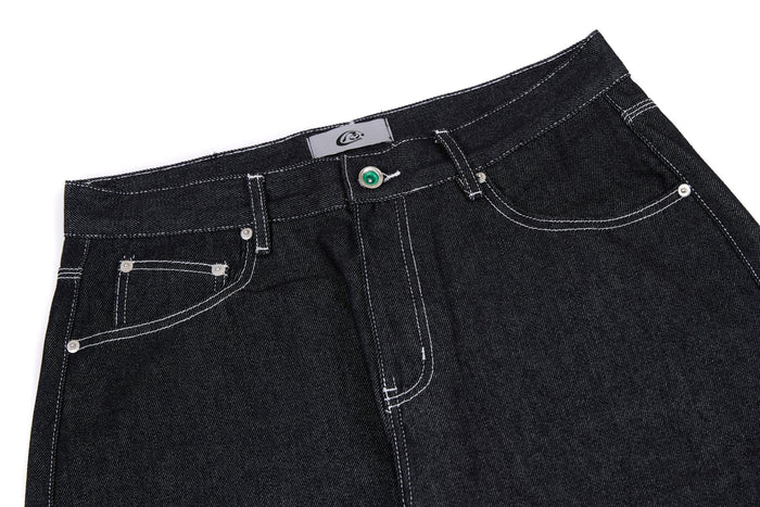 Close-up of black jeans waistband with button closure, belt loops, and front pockets