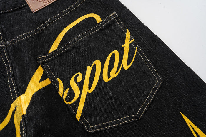 Back pocket close-up on black jeans with yellow script lettering