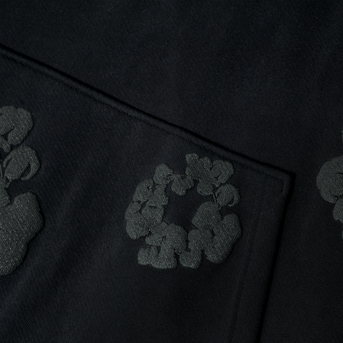 Close-up of the Black Monochrome “Cotton Wreath” Denim Tears Hoodie, a minimal streetwear sweatshirt with a subtle textured circular pattern and intricate weave, inspired by classic Denim Tears design.