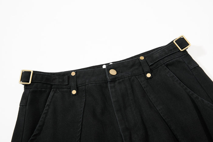 Close-up of black pants waistband with gold buckle belt loop and snap details