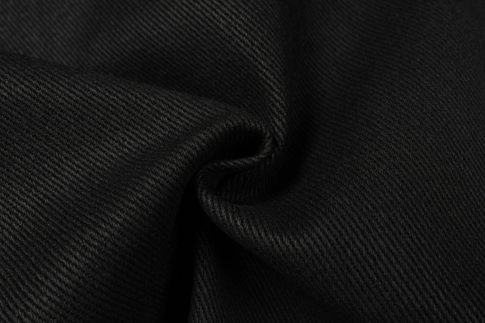 Extreme close-up of black denim fabric texture and fold detail