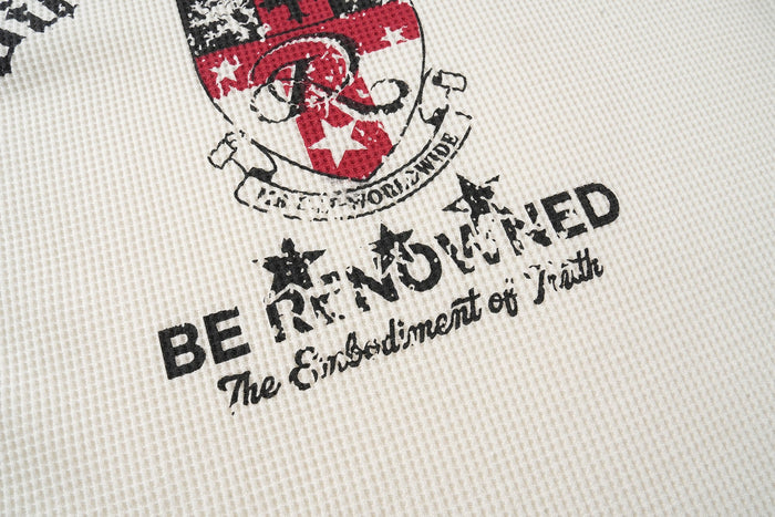 Close-up of a cream graphic tee with distressed red and black varsity-style camo print and bold text design