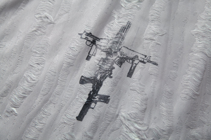 Distressed black rifle graphic on a white textured mesh patchwork tee, close-up detail of the fabric texture