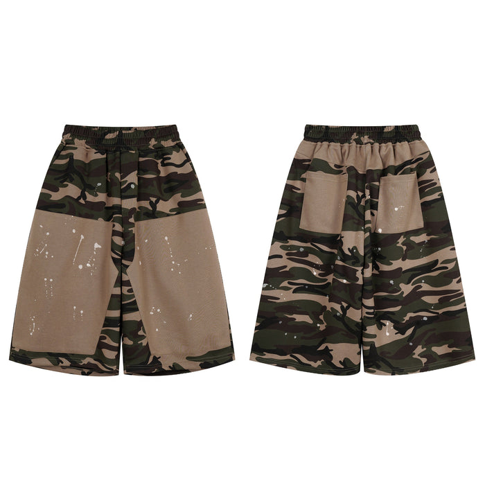 Front view of oversized camo patchwork baggy shorts with khaki contrast panels and white paint splatter detailing