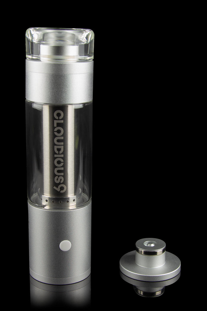 Silver cannabis e-rig with glass bubbler and disassembled magnetic base on a reflective black surface.