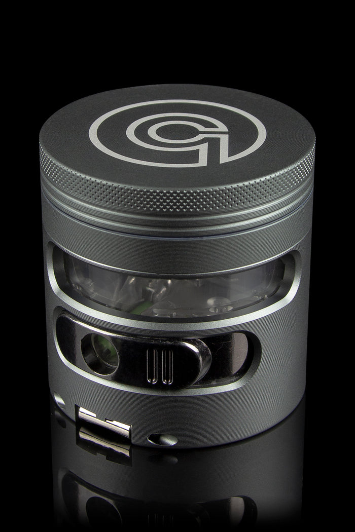 Black metal cannabis grinder with a clear center section, displaying green plant material.