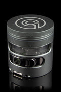 Black metal cannabis grinder with a clear center section, displaying green plant material.