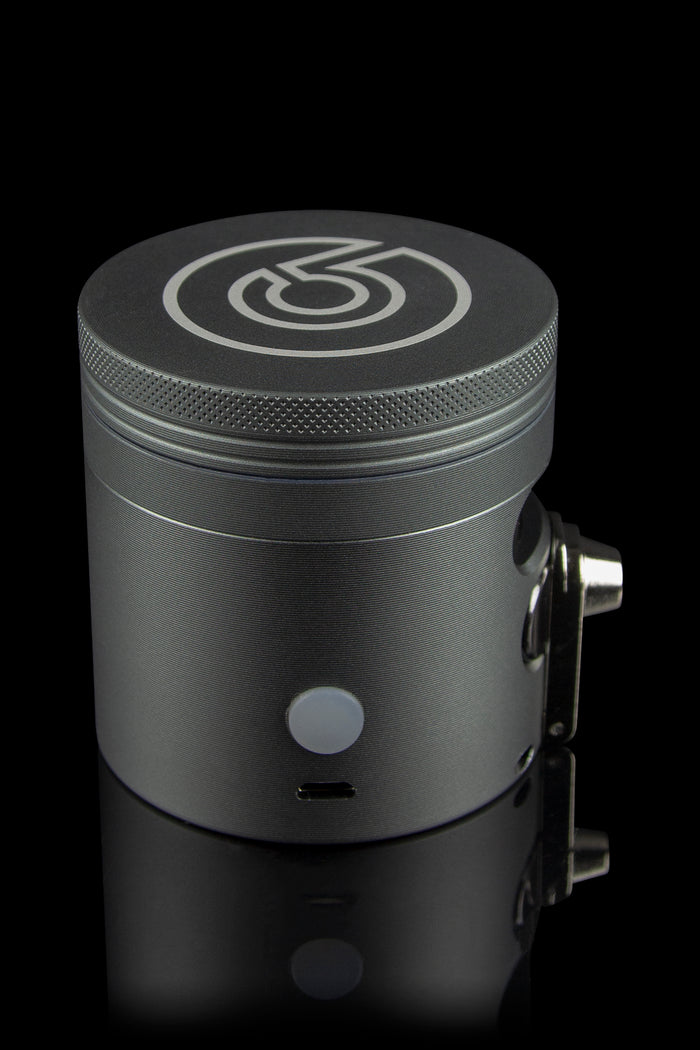 Sleek black cannabis grinder with a branded logo, displayed on a reflective surface.