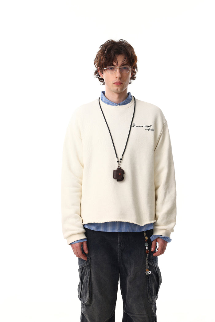 Model wearing cream sweatshirt with small chest text and black cord pendant