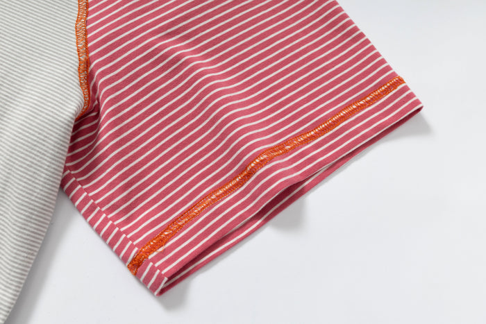 Close-up of pink and white striped raglan T-shirt sleeve with orange contrast stitching and color block detail