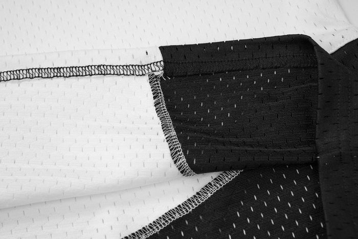 Close-up of jersey seam and mesh fabric where white body meets black sleeve panel