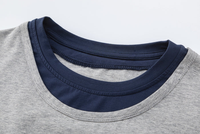 Close-up of a gray colorblock raglan T-shirt with navy contrast neckline and layered hem detail