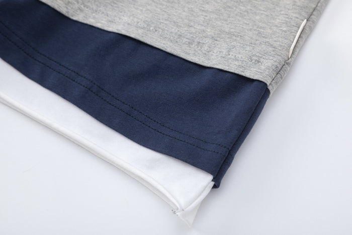 Close-up of a colorblock raglan T-shirt hem with heather gray, navy, and white layered fabric details