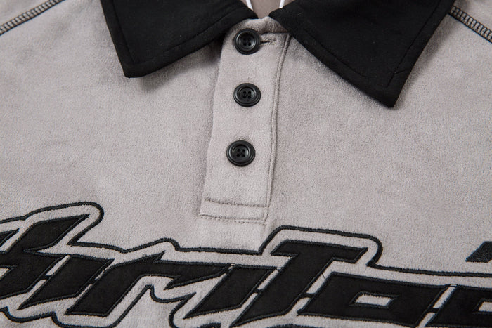 Close-up of button placket and black collar on the light gray polo shirt front