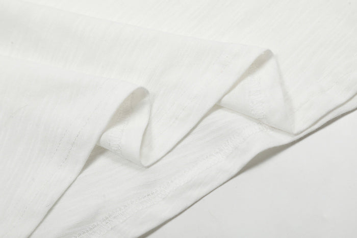 Close-up of white tee fabric showing smooth knit texture and seam stitching