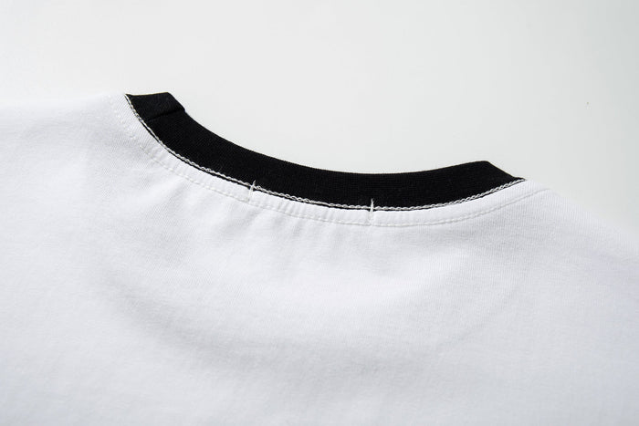 White ringer T-shirt with black ribbed crew neckline and visible top stitching on soft cotton fabric