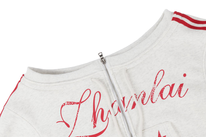 Close-up of off-shoulder neckline and front zipper on white hoodie with red script print