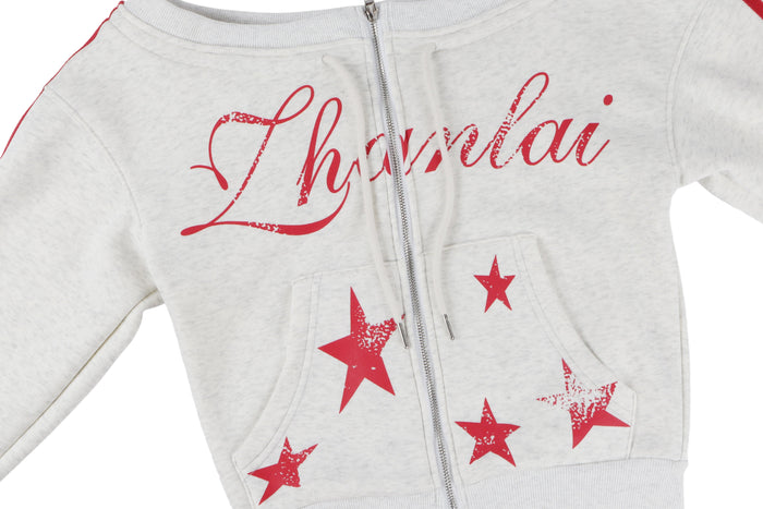 Front close-up of white zip hoodie with red script text and star graphics