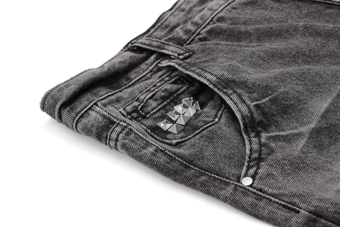 Close-up of front pocket with silver pyramid studs on distressed denim