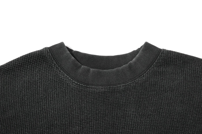 Close-up of a dark waffle knit graphic T-shirt with a ribbed crew neckline and vintage washed texture