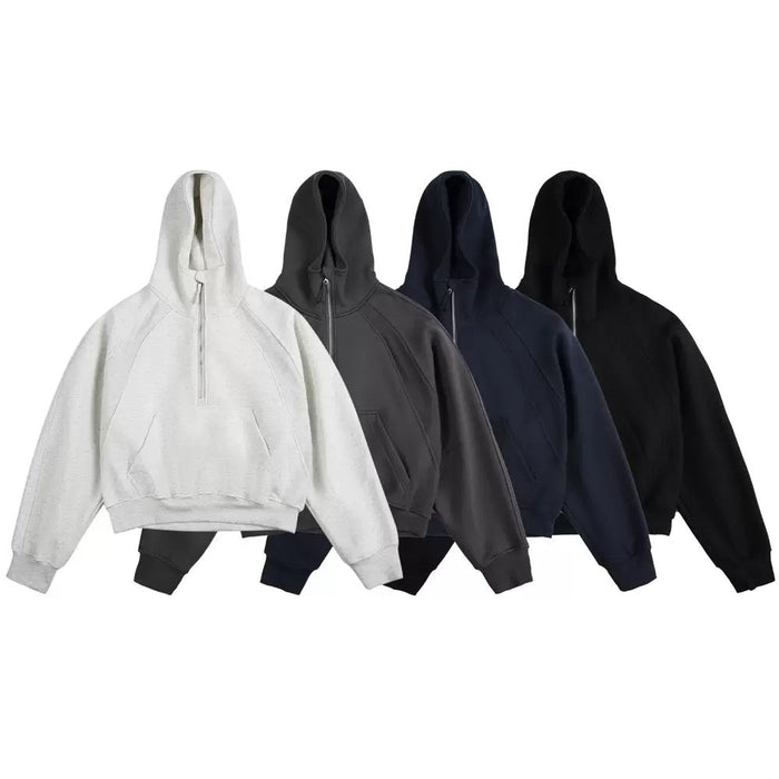 Four half-zip cropped hoodies displayed in light grey, charcoal, navy, and black colorways on a white background