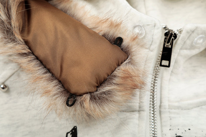 Close-up of hoodie hood lining and zipper pull beside faux-fur trim