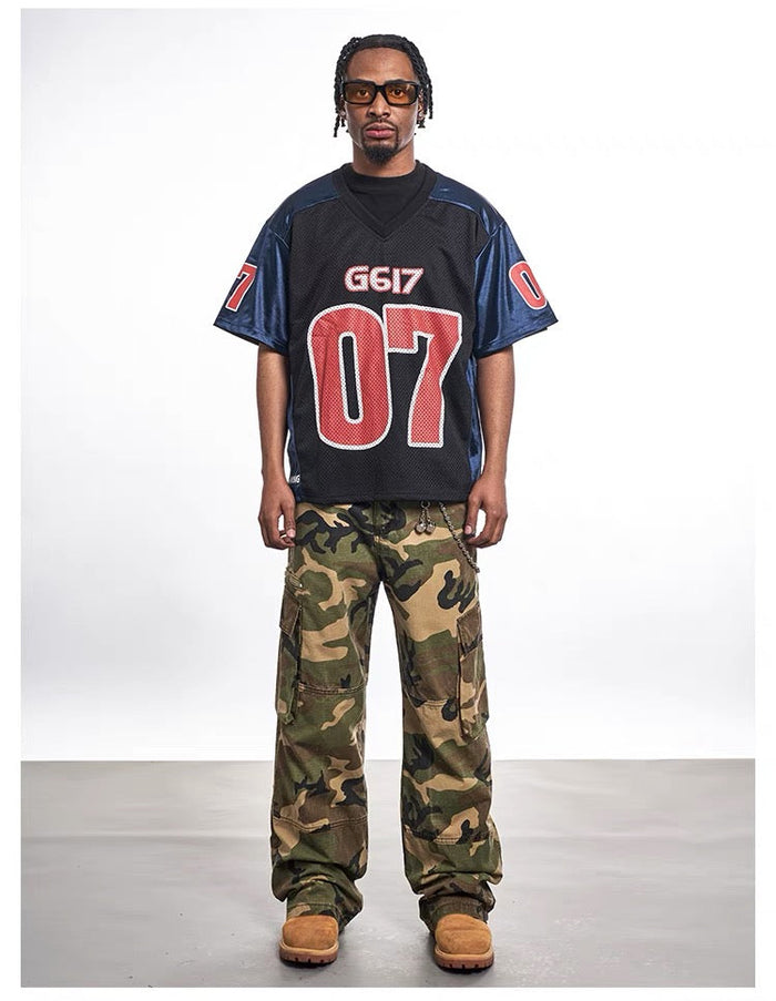 Oversized black mesh varsity jersey tee with red 07 graphic, worn with camo cargo pants and tan boots