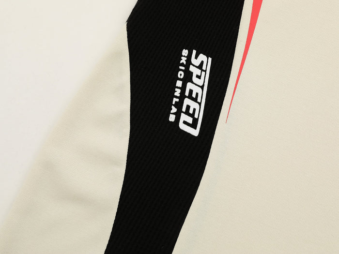 Close-up of a cream athletic tee with black SPEED logo stripe and red accent detail