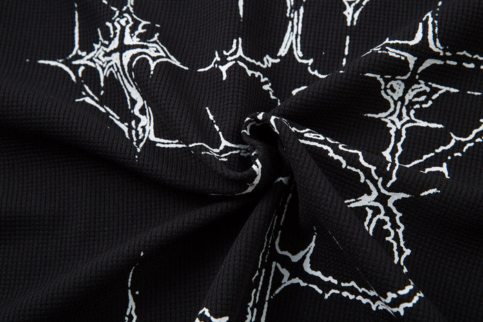 Close-up of black polo shirt fabric with white gothic thorn cross graphics and textured dark streetwear style