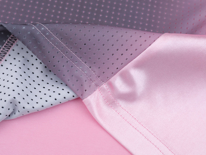 Close-up of pink and gray mesh jersey panels with visible stitching and perforated racing-style fabric texture