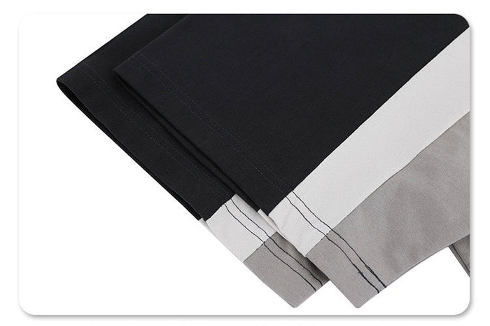 Black colorblock T-shirt with white and gray panels, shown folded to highlight the futuristic streetwear design