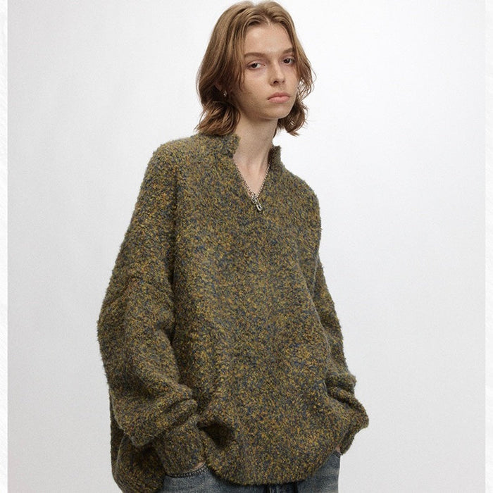 Model wearing olive and gray speckled boucle sweater with relaxed sleeves and half-zip collar