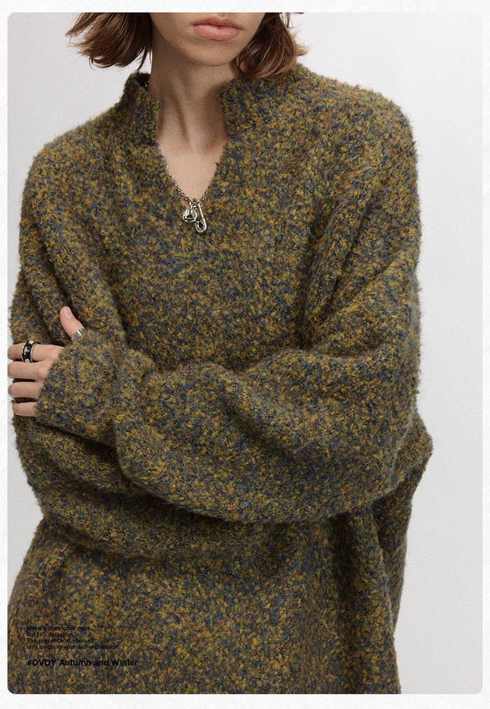 Close-up of olive speckled boucle pullover on model with half-zip neckline and wide sleeves