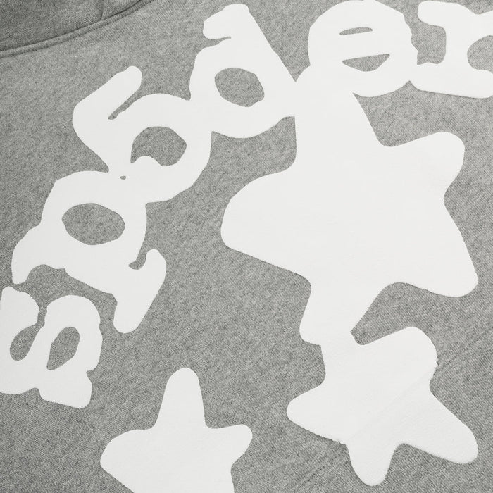 Close-up of the Sp5der Stars Hoodie – Grey 440GSM Heavyweight Streetwear Pullover, showcasing bold white text and playful abstract star shapes in a bubbly font for an eye-catching look.