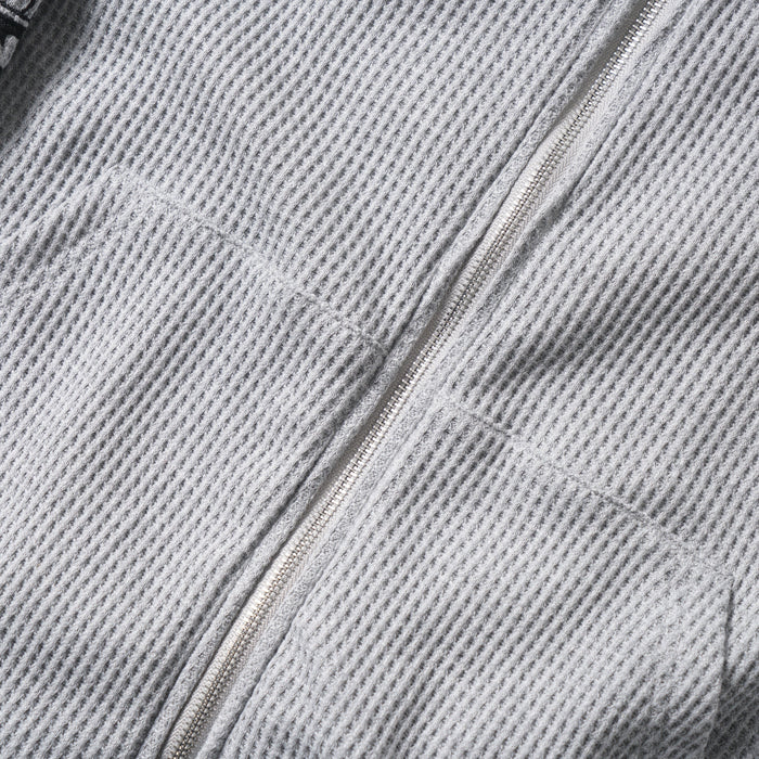 Close-up of the front zipper and waffle knit texture on the gray hoodie