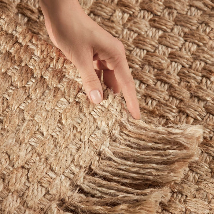 Hand touching a textured woven mat with fringes